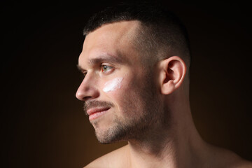 Obraz premium Handsome man with cream on his face against dark background