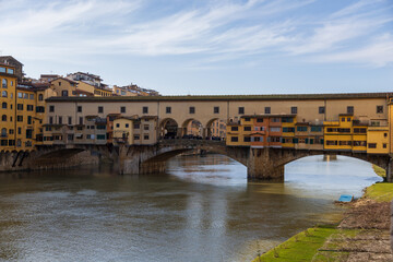 Obraz premium Florence Bridge Scene. Colorful Riverside Structures With Reflection. Sunlit Cityscape Featuring Architecture And Water Reflections In Florence