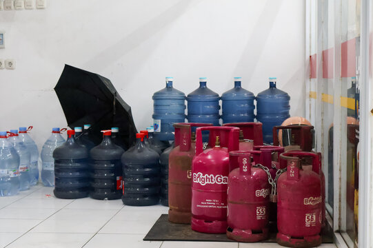 Balikpapan-Indonesia February 1st, 2026 Stack of pink Pertamina Bright Gas cylinders and large blue water gallon bottles arranged indoors in Indonesia, reflecting local household energy and water supp
