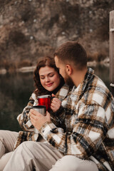 Couple enjoys warm drinks together by a lake on Valentines Day in a cozy setting