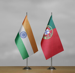 Two table flags of India and Portugal on a blurred gray background