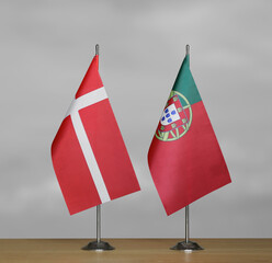 Two table flags of Denmark and Portugal on a blurred gray background