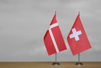 Two table flags of Denmark and Switzerland on a blurred gray background