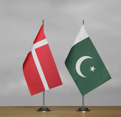 Two table flags of Denmark and Pakistan on a blurred gray background