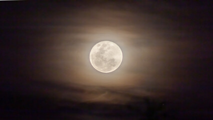 Full moon in the dark night sky with clouds,