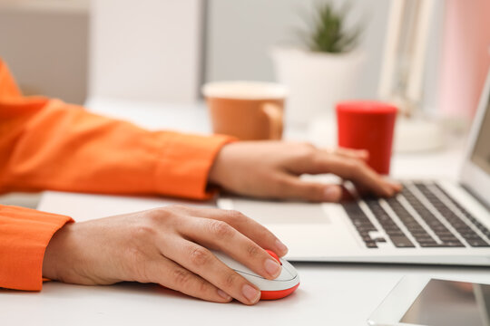 Hands of woman using computer mouse and laptop at table in office