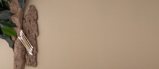 Wood cotton swabs on natural bark, green leaves