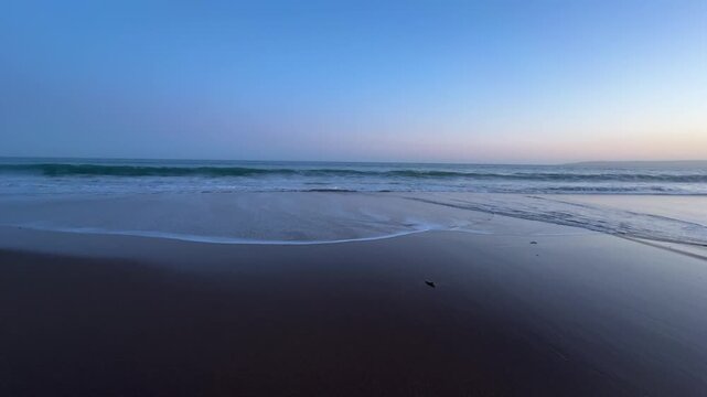 calm waves coming towards camera on beach at sunset dusk