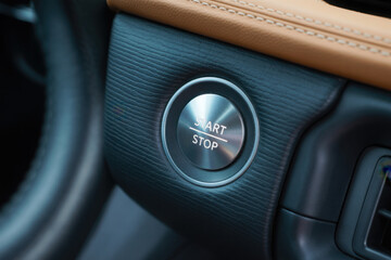 Car interior with illuminated start stop button set in textured leather dashboard, signaling readiness for urban commute or road trip.
