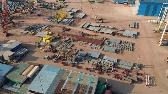 Aerial drone view capturing a vast heavy-industry fabrication yard with numerous structural components.