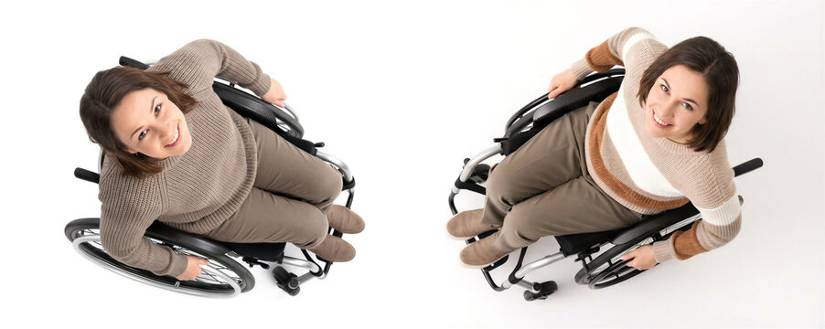 High angle view of two cheerful young women sitting in manual wheelchairs on white background