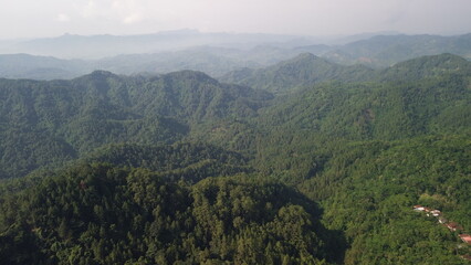 Obraz premium Aerial view of a row of green hills, with lush trees in the morning in Indonesia