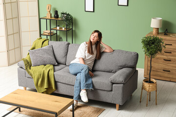 Obraz premium Beautiful young woman resting on cozy sofa in living room