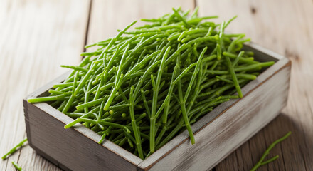 A small wooden crate overflows with vibrant green sea beans, also known as samphire, resting on a rustic light-colored wooden table. Generative AI