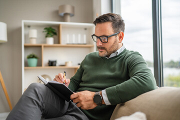 Man wearing eyeglasses reading notebook by window relaxation