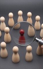 Obraz premium Magnifying glass highlights one red pegman among many beige ones, symbolizing focus or selection.