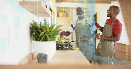 Stirring frying pan, senior and son wearing gray aprons talking at kitchen counter with gas cooktop