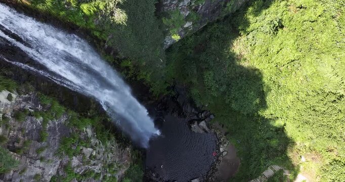Aerial drone hover shot of Jade Curtain Waterfall (Yu Lian Spring) on Mount Lu, Overhead view captures plunging cascade amid cliffs, forest, and serene pool.  Jiangxi Province, China.
