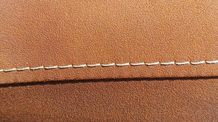 Close up of neat white thread stitching on brown synthetic leather. For graphic design, 3D rendering and banners