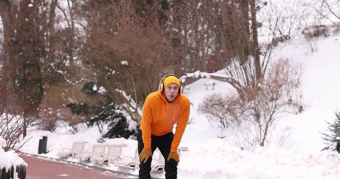 Man with headphones stopping for rest during run in winter park