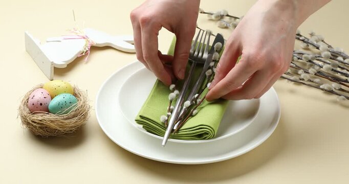Easter celebration. Woman setting table for festive dinner on beige background, closeup