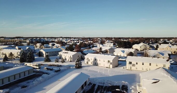 Aerial drone video of apartment buildings and private houses in a nice quite suburban subdivision on a sunny winter day after getting covered with snow the day before.