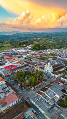 Obraz premium This vibrant aerial shot captures the colorful rooftops and bustling square of Filandia, Colombia, against a stunning sunset sky.