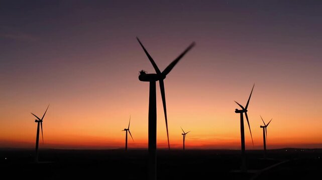 Wind turbines generating electricity at dusk with vibrant sky.