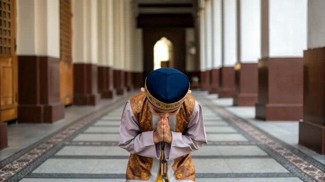 Young boy praying traditional clothing prayer mosque corridor child worship cultural dress religious practice serene bowing hands together peaceful