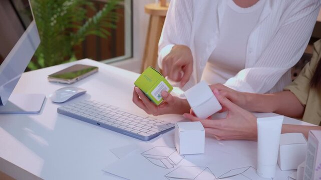 Hand holding cosmetic packaging mockup box, graphic designer and development branding project, sketch and layout artwork, business startup planning creative for skincare product label advertising.