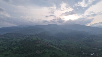 Fototapeta premium Serene Green Mountain Landscape with Hazy Valleys Under Cloudy Sky