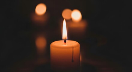 single candle flame burning in dark background