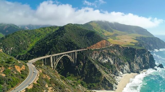 Scenic aerial view of a concrete arch bridge along the California coastline.