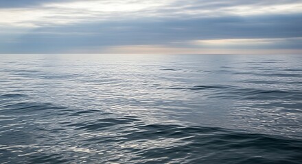 Obraz premium Calm Ocean Waters Reflecting a Cloudy Sky at Dusk.