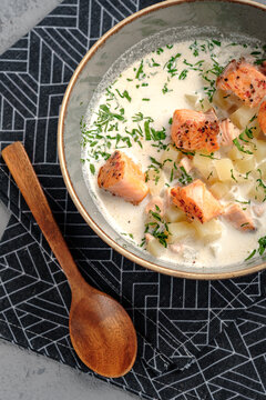 Creamy Finnish salmon soup (lohikeitto) with tender grilled salmon chunks, diced potatoes and fresh dill garnish in rustic bowl. Traditional Nordic fish chowder, top view