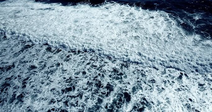 Cinematic scene Aerial view Top down aerial view of beautiful giant blue ocean waves crashing and foaming with white wash background. High quality video 4K prores422