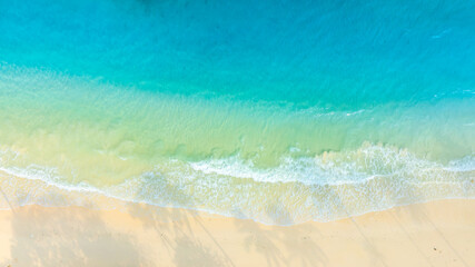 Obraz premium Top view show waves crashing onto a tropical coastline with crystal-clear blue waters contrasting with sandy beaches and coral reefs off the shore of a tropical island with emerald-green waters. 