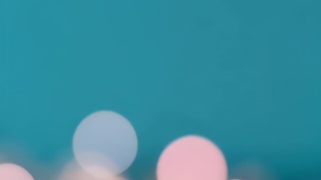 Slow motion colorful bokeh orbs drifting on dark blue background. Abstract light spots in pink and white tones. Floating bubbles effect for digital video animation concept