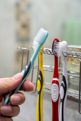Hanging toothbrush on holder in bathroom, daily oral hygiene routine concept