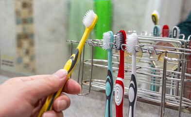 Hanging toothbrush on holder in bathroom, daily oral hygiene routine concept