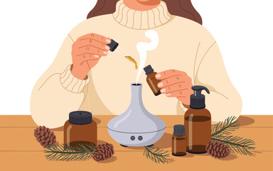 A woman using an essential oil diffuser on a wooden table surrounded by pinecones and bottles of oil