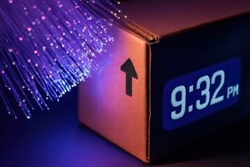 drop shipping store box clock logistic concept. Clock with glowing fibers showing time in a dark setting.