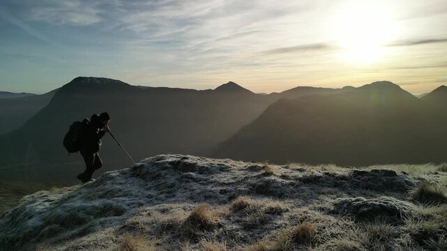 Glen Coe, Scottish Highlands - aerial over the mountains in winter with hill walker hiking through frame