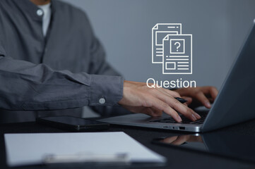 Person typing on laptop with printed documents and question symbol