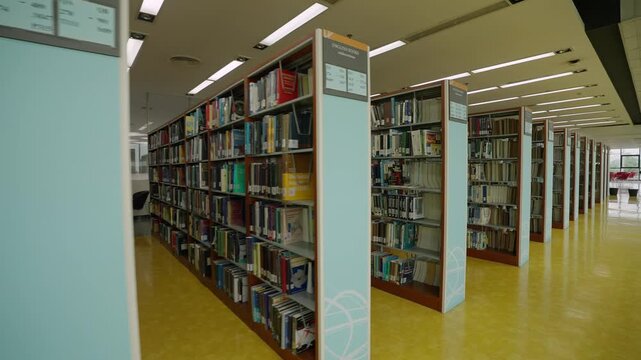 Interior of a university library with bookshelves arranged in rows at a university in Bangkok, Thailand.