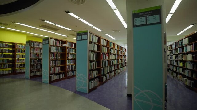 Interior of a university library with bookshelves arranged in rows at a university in Bangkok, Thailand.