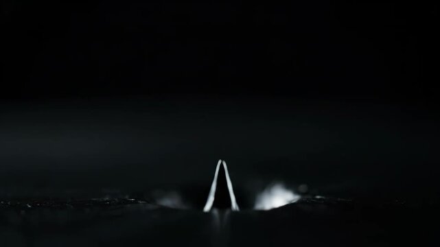 A captivating close-up of a liquid spike rising and falling, showcasing intricate fluid dynamics and ripples.