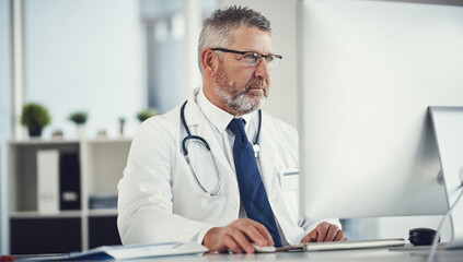 Fototapeta premium Medical, research or doctor in clinic with computer, telehealth or record check for patient diagnosis. Healthcare, space or mature man with tech, online advice or evaluation result in hospital report