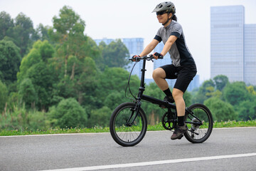 Naklejka premium Riding a fold bike with modern city in the distance
