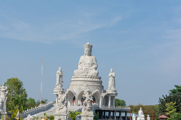 Grand Chinese Buddha statue atop temple staircase under clear blue sky, serene spiritual landmark in Thailand